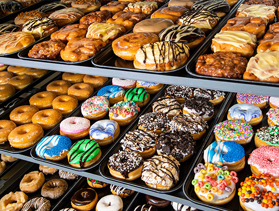 A display case filled with a variety of donuts, made from frozen dough supplied by Baker Boy.